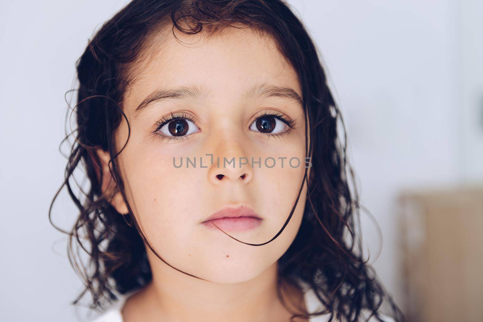portrait of a serious little girl with wet hair after taking a bath, kids hygiene concept