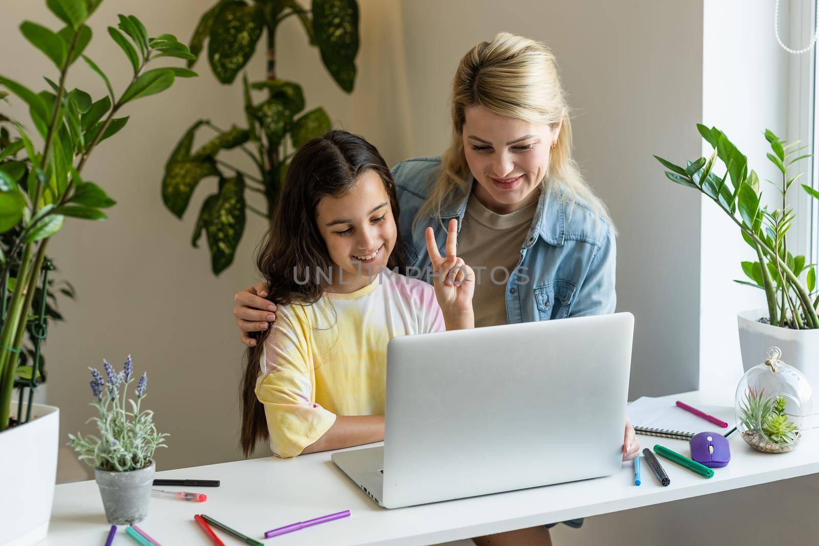 Beautiful mother and child looks at laptop screen spend time in kitchen using app education program, choose cartoons, teach kid pc usage, controls what daughter watching on internet cyberspace concept