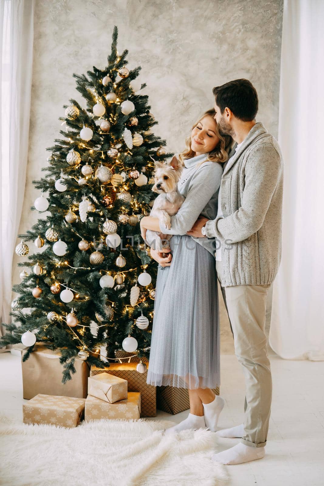 Happy family: mom, dad and pet. Family in a bright New Year's interior with a Christmas tree.