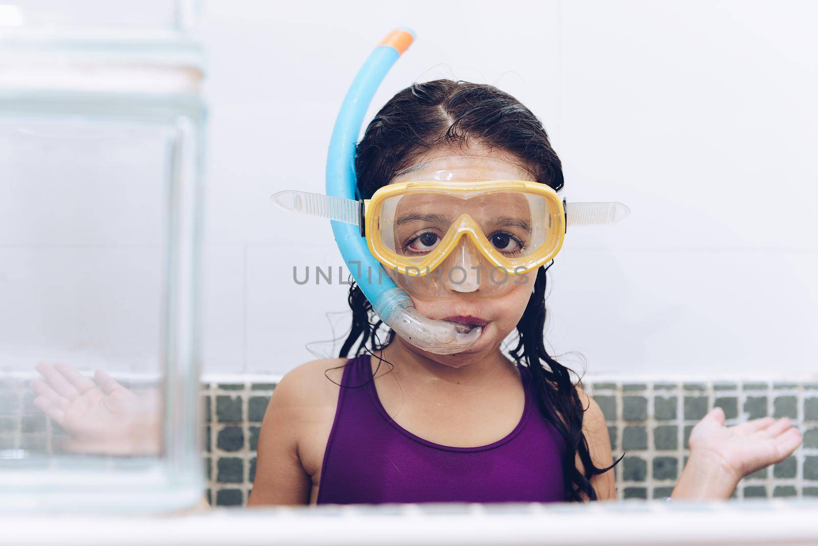 portrait of a funny pretty little girl asking what with snorkel goggles in the tub while taking a bath in the bathtub, kids hygiene concept, copy space for text