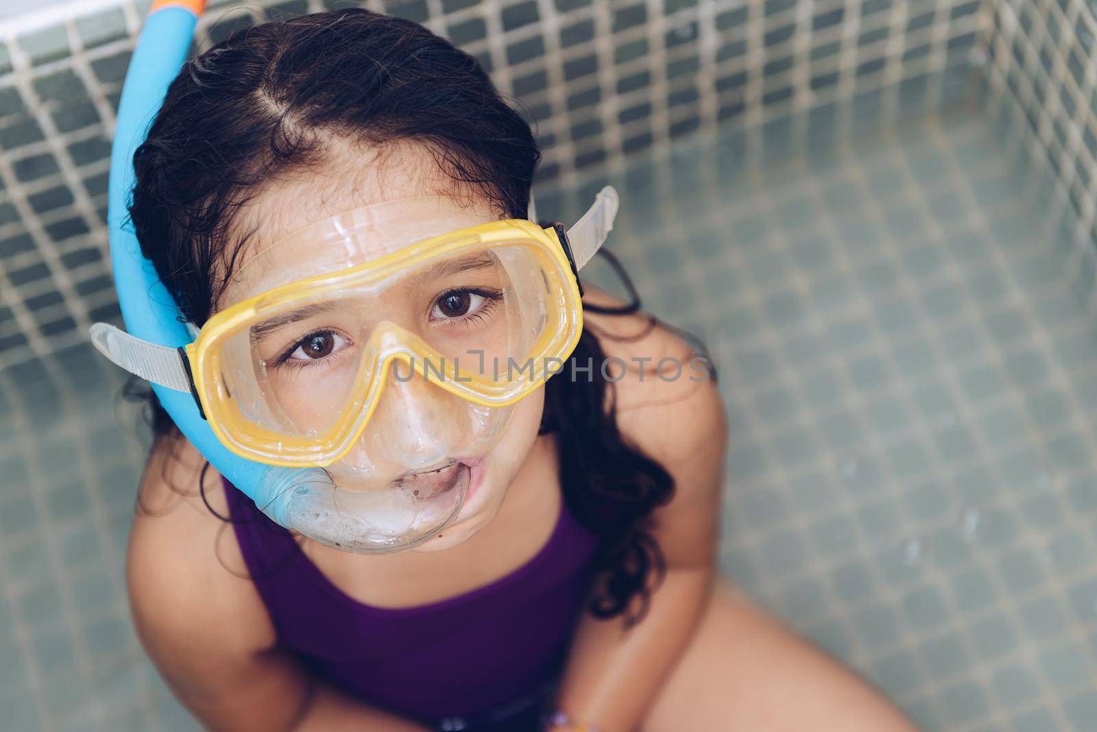 portrait of a pretty little girl having fun with snorkel goggles sitting in the tub while taking a bath in the bathtub, kids hygiene concept, copy space for text
