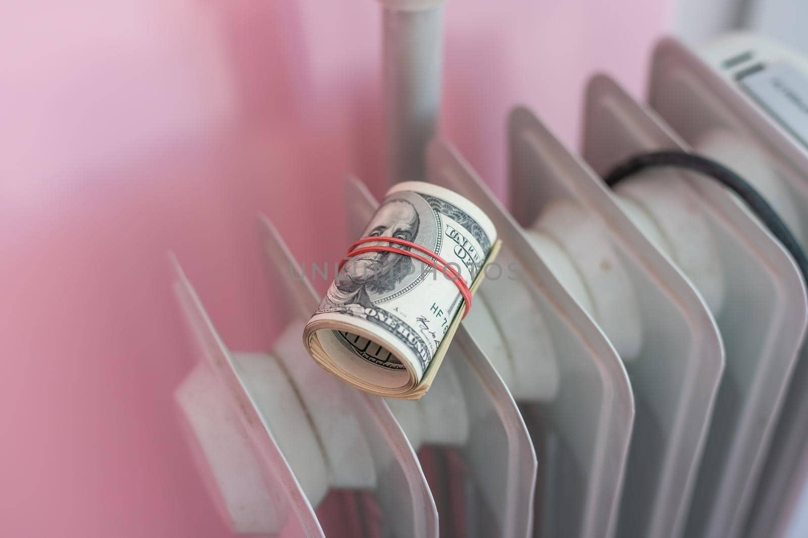 Radiator with dollar banknotes, closeup. Concept of heating season