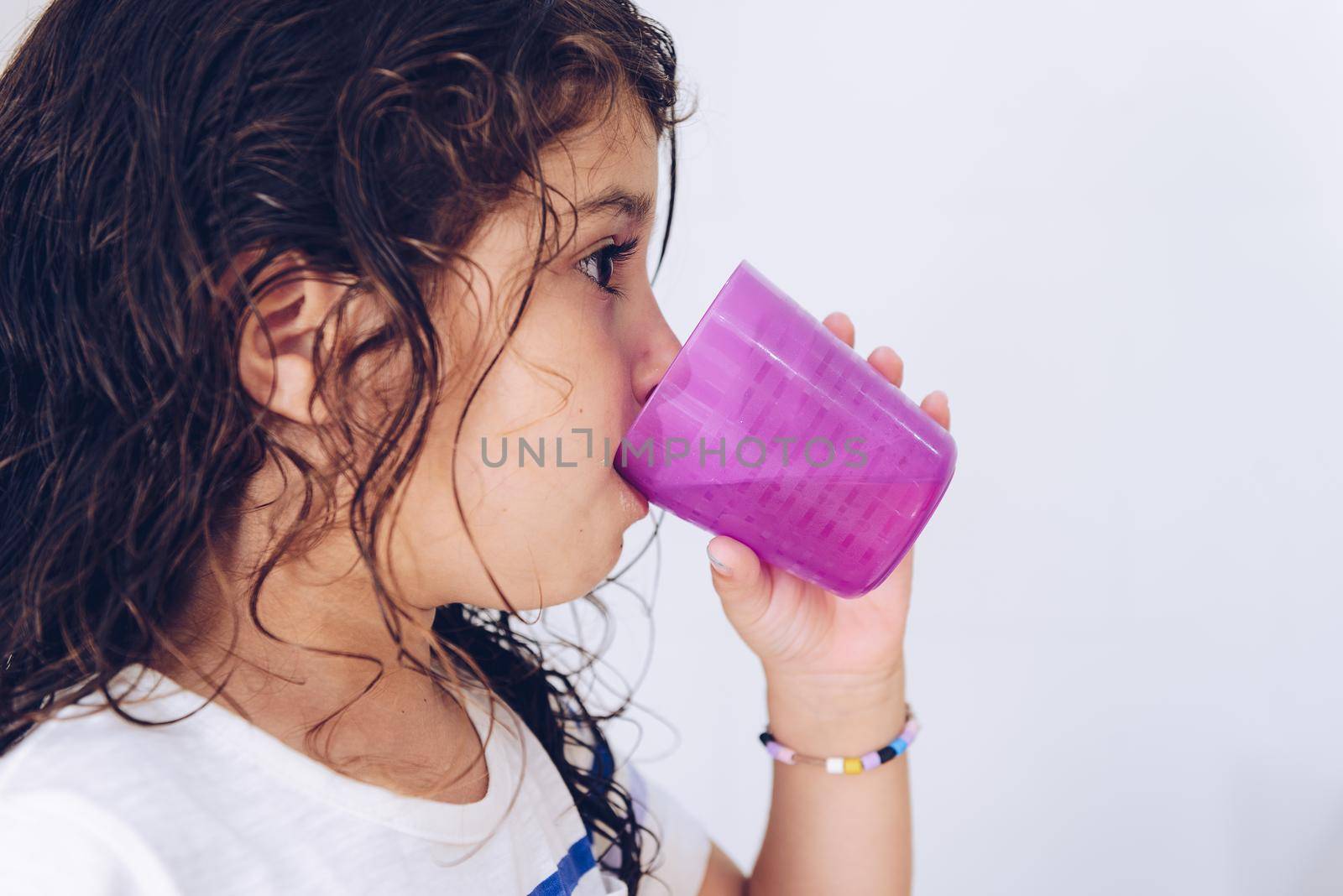 portrait of a little girl rinsing her mouth after brushing teeth in the bathroom before going to bed after taking a shower, kids hygiene concept, copy space for text