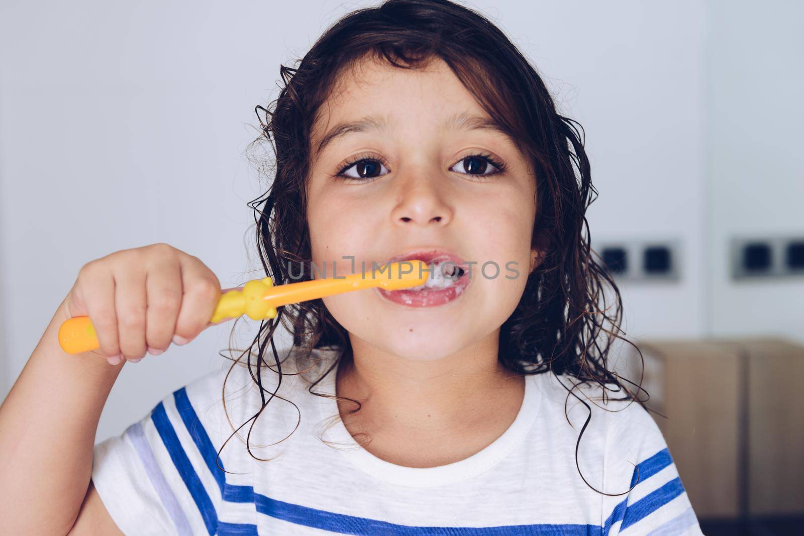 portrait of a little girl brushing her teeth in the bathroom before going to bed after taking a shower, kids hygiene concept