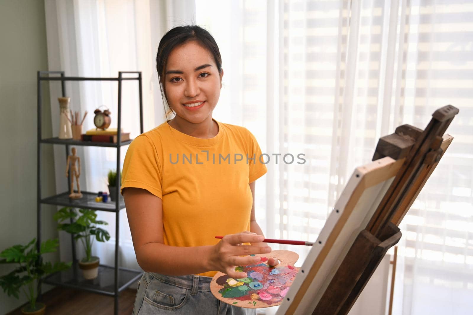 Female artist painting picture with watercolor in bright daylight studio. Art, creative hobby and leisure activity concept.