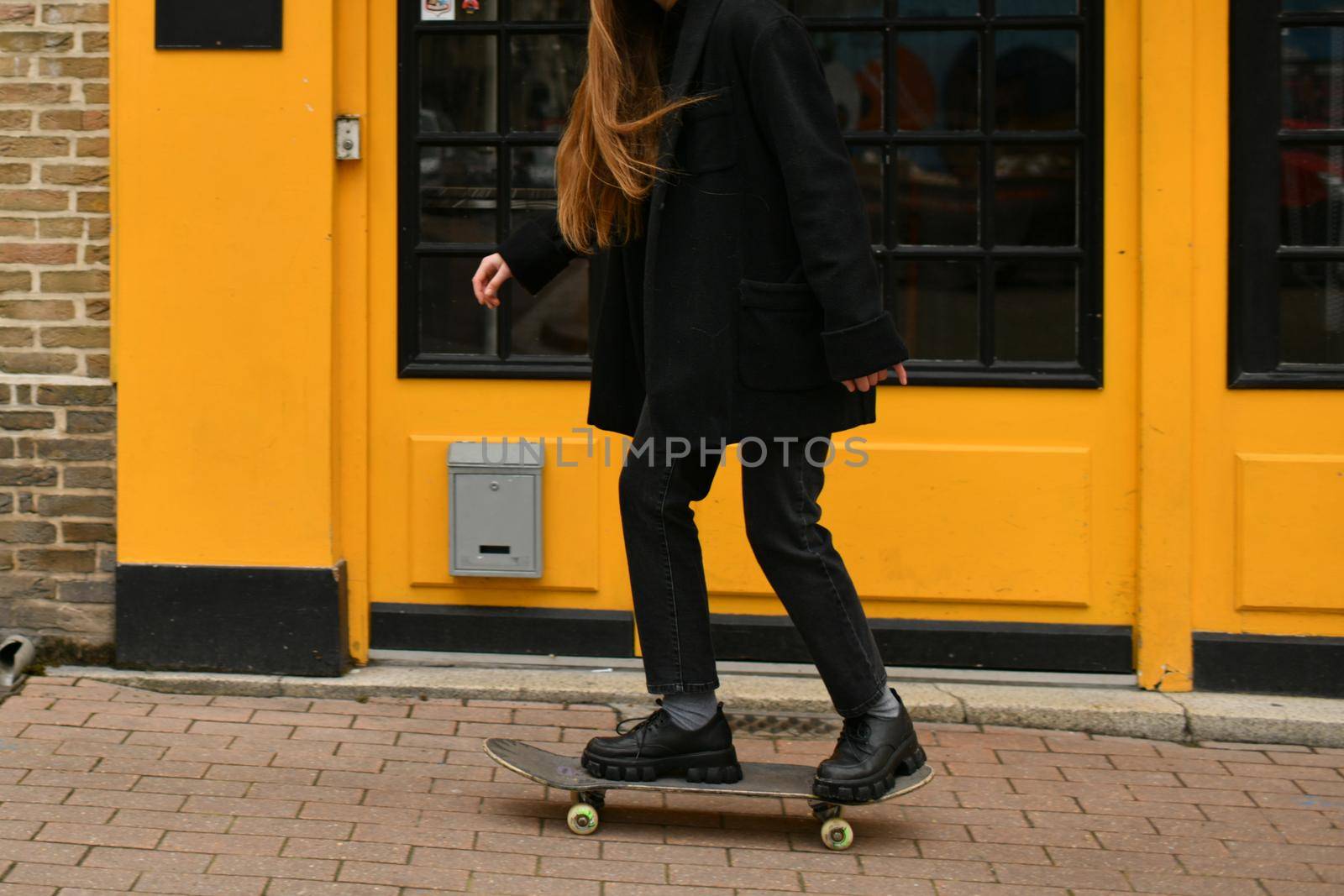 A girl near yellow wall with a skateboard