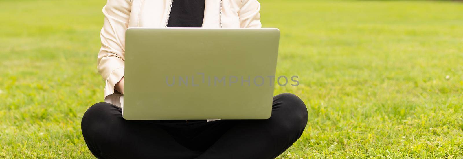 Young woman using laptop in the park by Andelov13