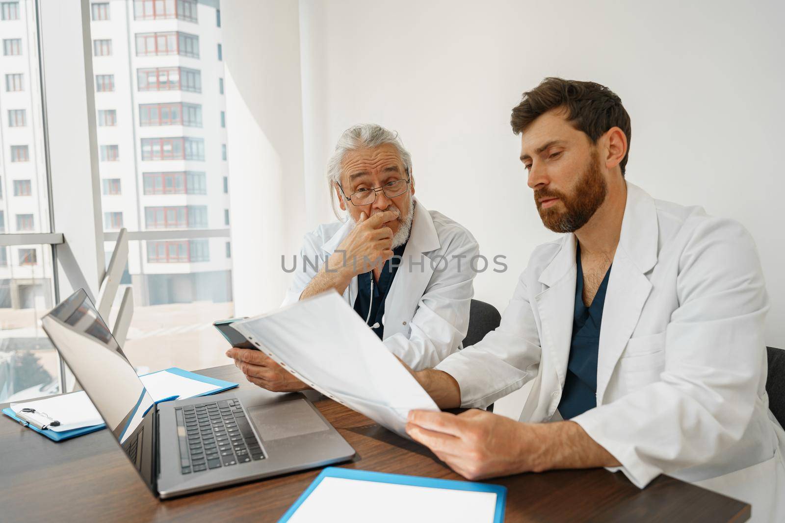 Two doctor colleagues discussing patient diagnosis sitting in office of medicine clinic