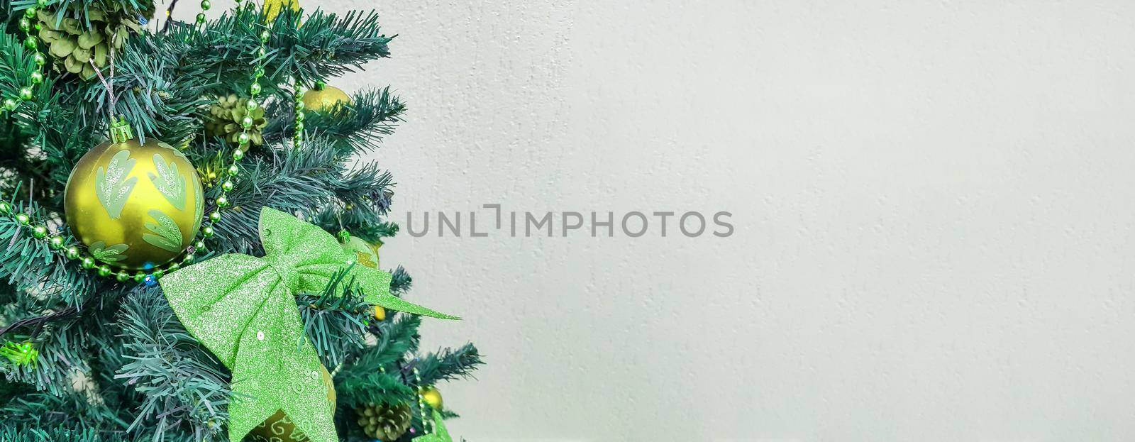 Banner with a Christmas tree decorated with bows, sparkling glass balls and Christmas tree toys close-up with an empty copy space on the right.