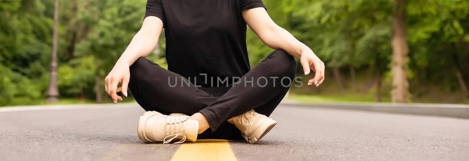 Joyful young lady in casual clothes walking along asphalt road in countryside, hitchhiking for ride outdoors. Lovely millennial woman traveling alone by autostop by Andelov13