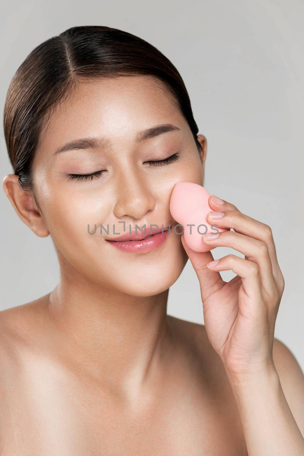 Closeup ardent woman applying her cheek with dry powder and looking at camera. Portrait of younger with perfect makeup and healthy skin concept.