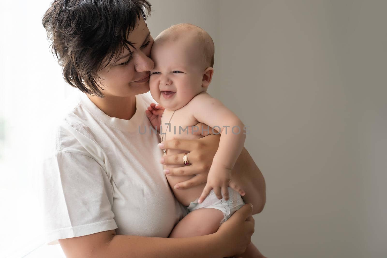 Mother holding baby in white bedroom by Andelov13