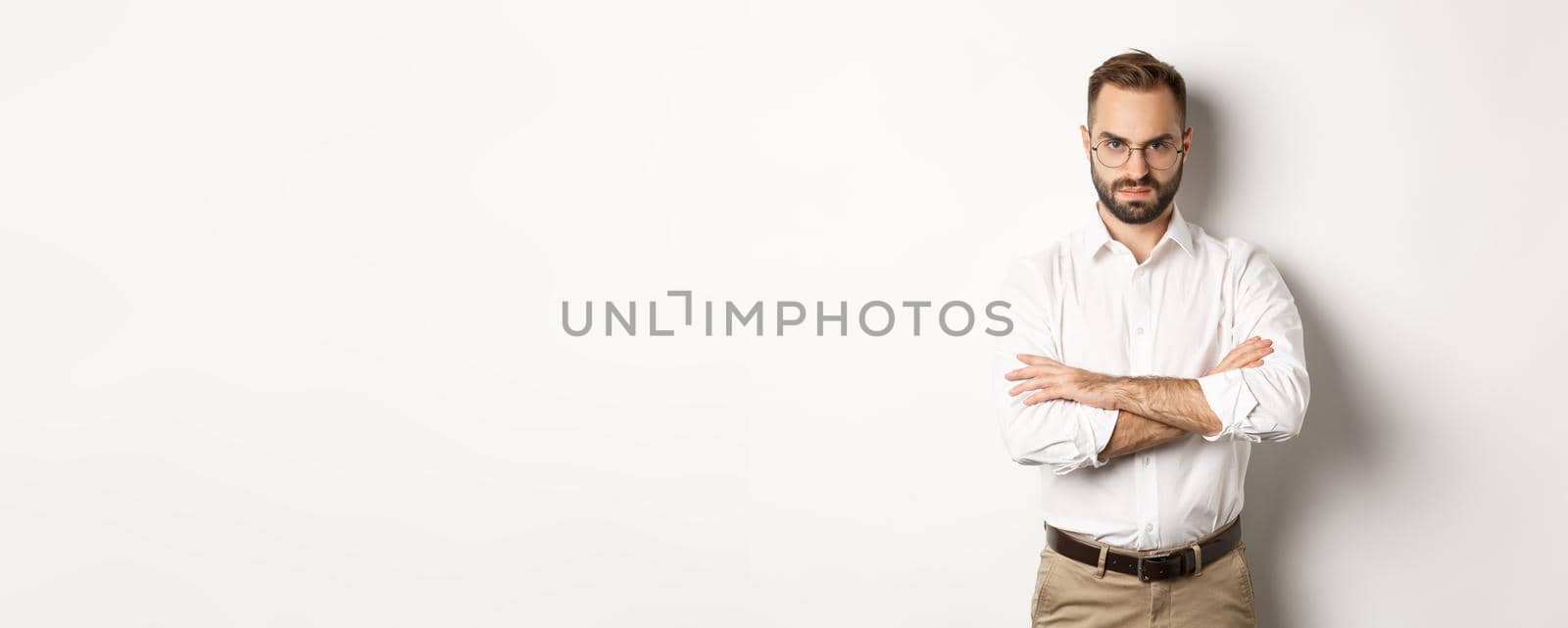 Angry manager looking disappointed, cross arms on chest and frowning displeased, standing over white background. Copy space