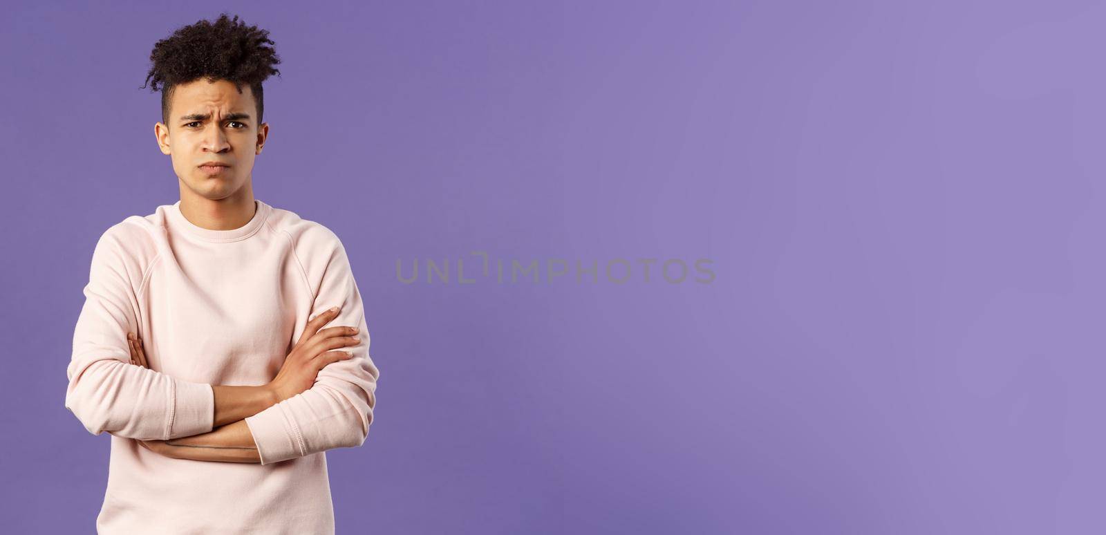 Portrait of young offended hispanic boyfriend, frowning and looking judgemental upset at camera, cross hands over chest defensive insulted pose, standing purple background angry at someone.