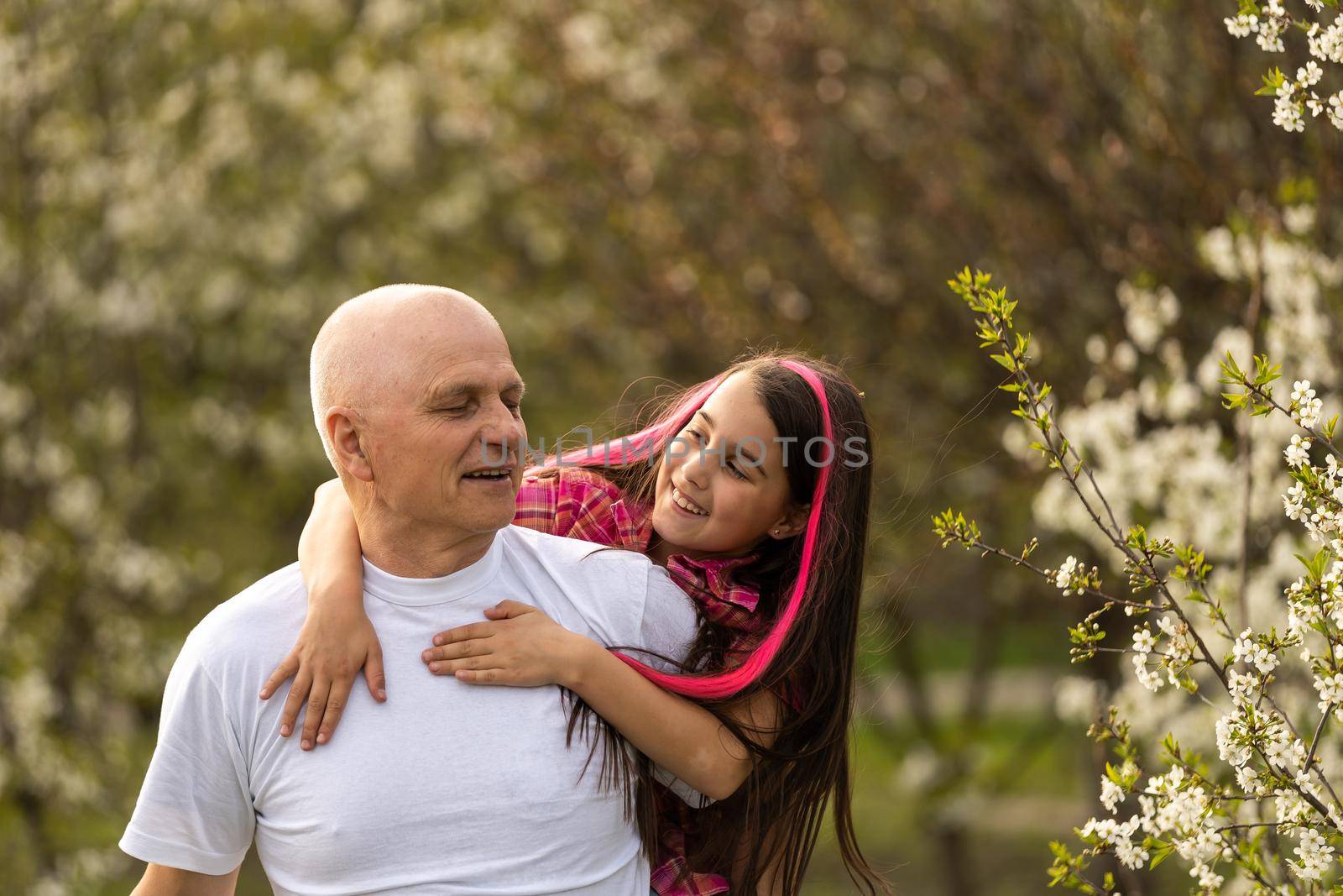 Adorable cute girl and grandfather walk in park