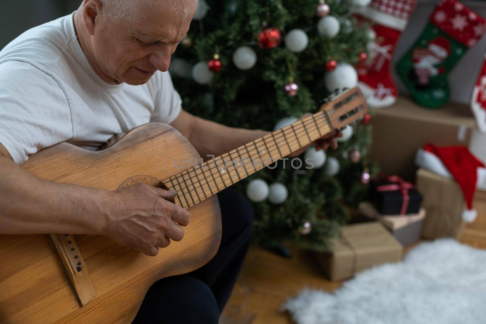 Happy people family concept - Old senior man enjoying the guitar on the sofa in the house at christmas by Andelov13