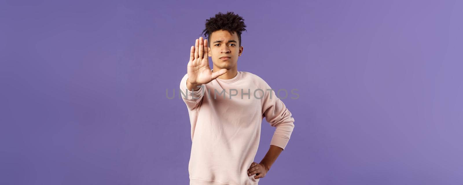 Portrait of confident serious-looking determined young man trying to prevent something, pull hand in stop gesture, look camera assertive, prohibit, give warning or forbid something.