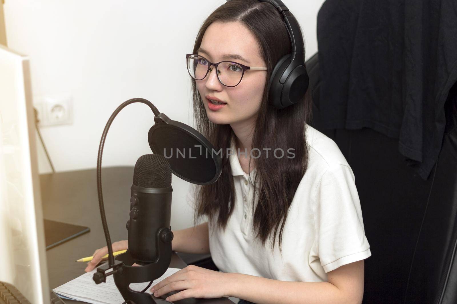 Young woman with glasses, microphone and headphones recording podcast at studio, professional record audio, technology and media concept