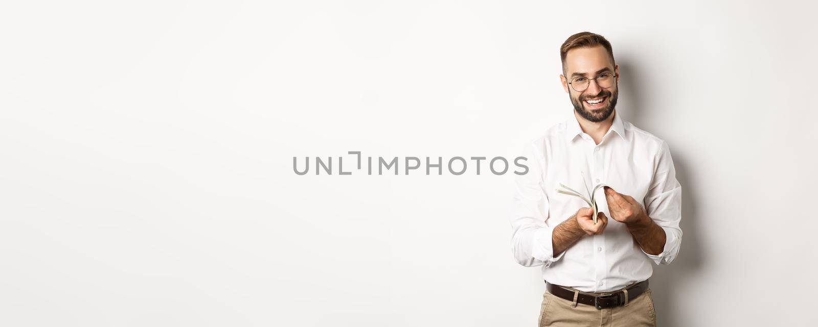 Successful businessman in white shirt, counting money and smiling satisfied, standing over white background by Benzoix