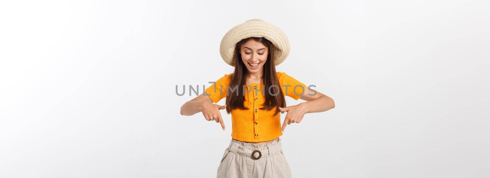 Teenager girl on summer vacation surprised and pointing finger on copy space over isolated white background