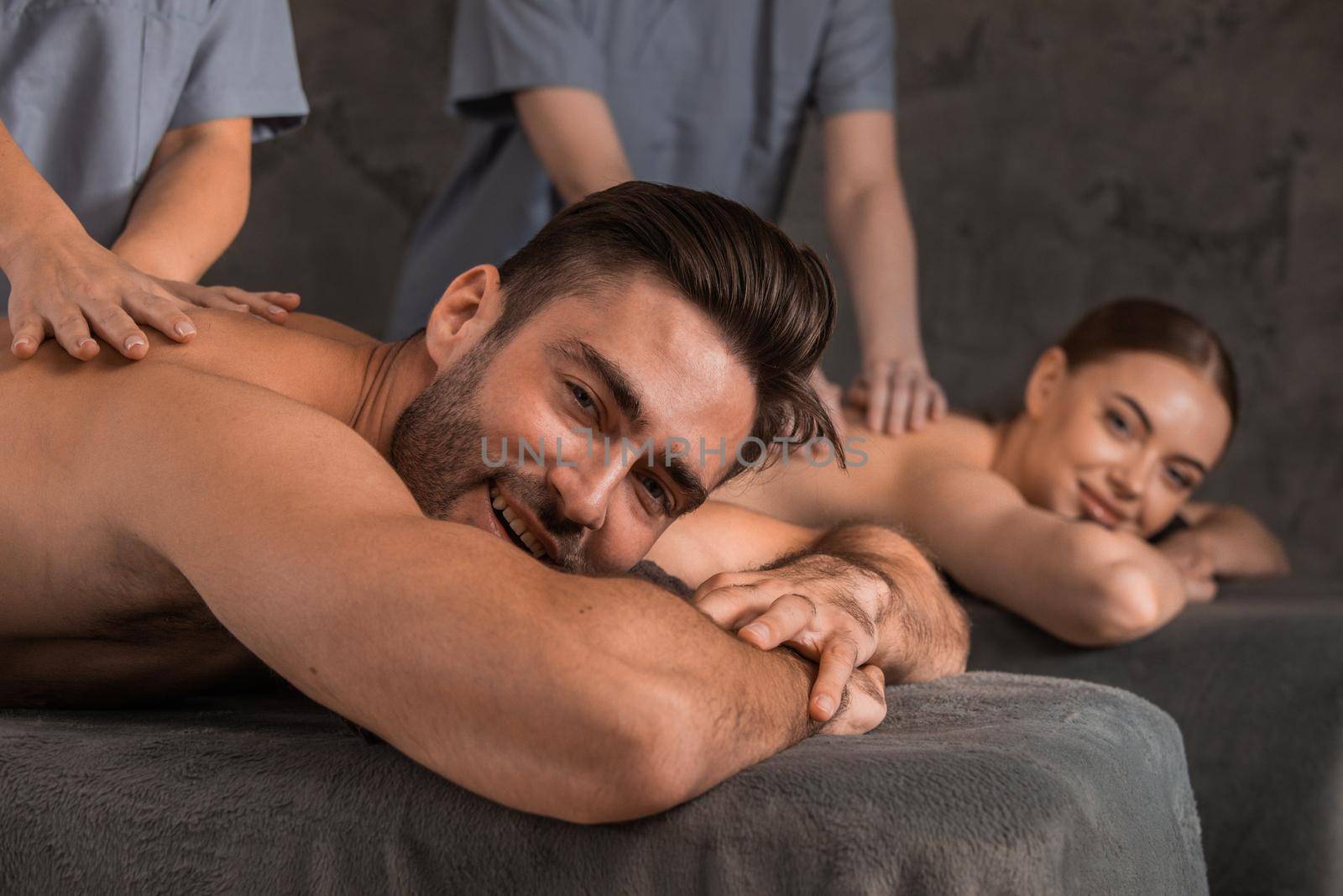 Happy young couple enjoying spa procedures, back massage