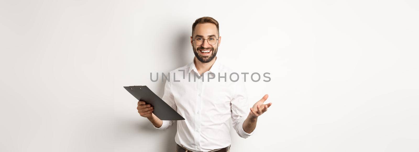 Handsome boss looking satisfied, holding clipboard and praising you, standing over white background by Benzoix