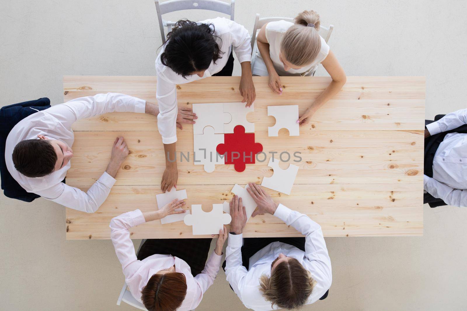 Diverse business people assembling puzzle by ALotOfPeople