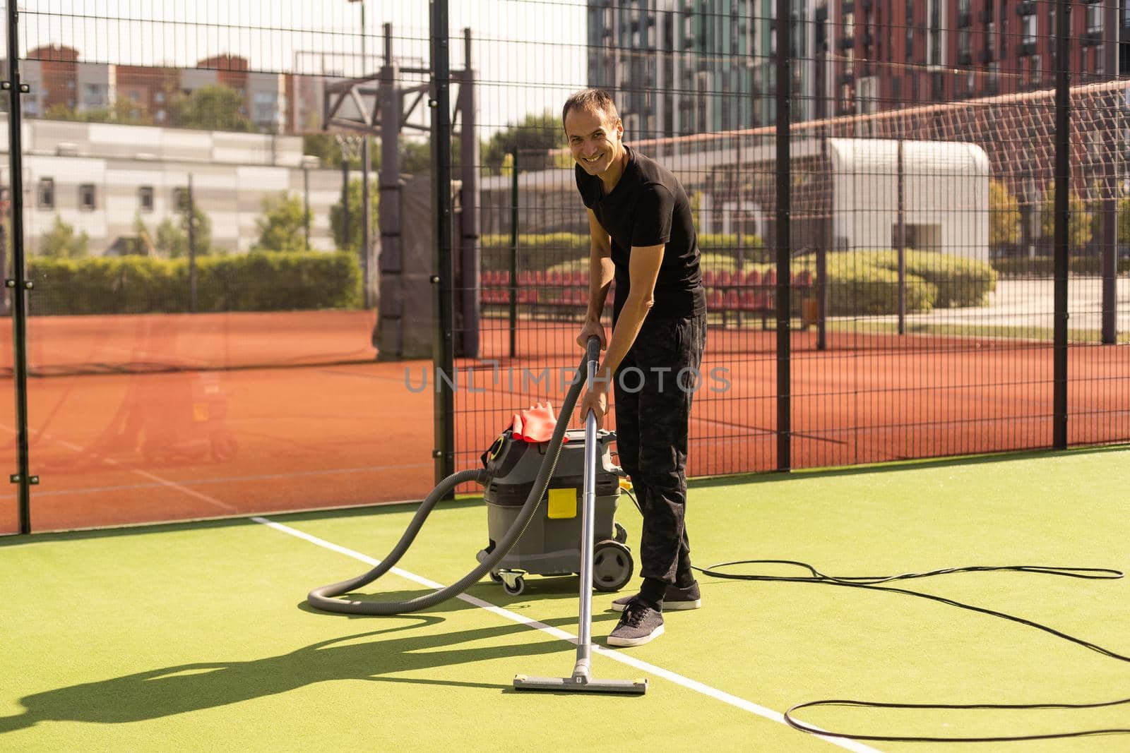 The boy cleaning tennis court clay surface after the match to prepare for the next match.