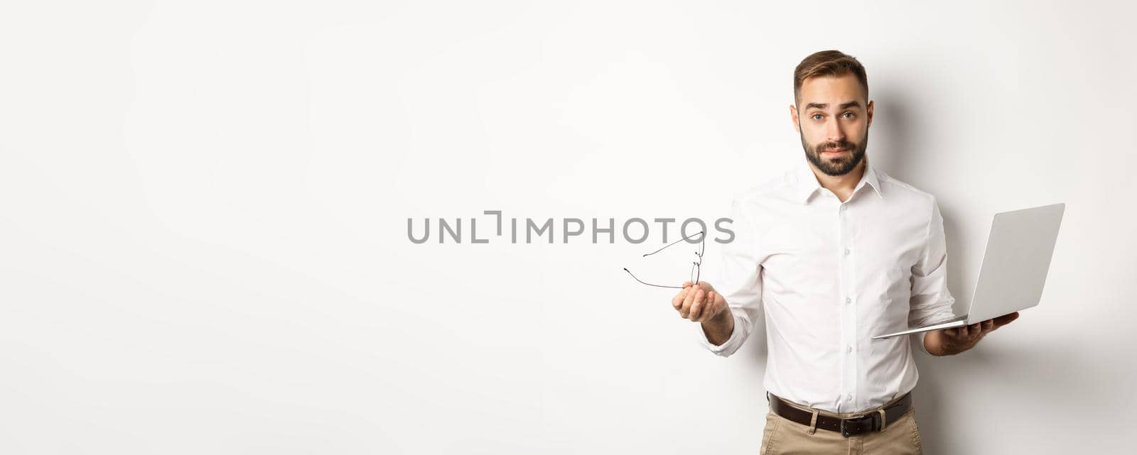 Business. Handsome businessman looking confused after working with laptop, standing against white background by Benzoix