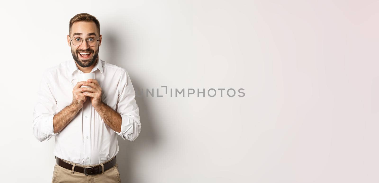 Man drinking coffee and looking excited, enjoying drink, standing over white background by Benzoix