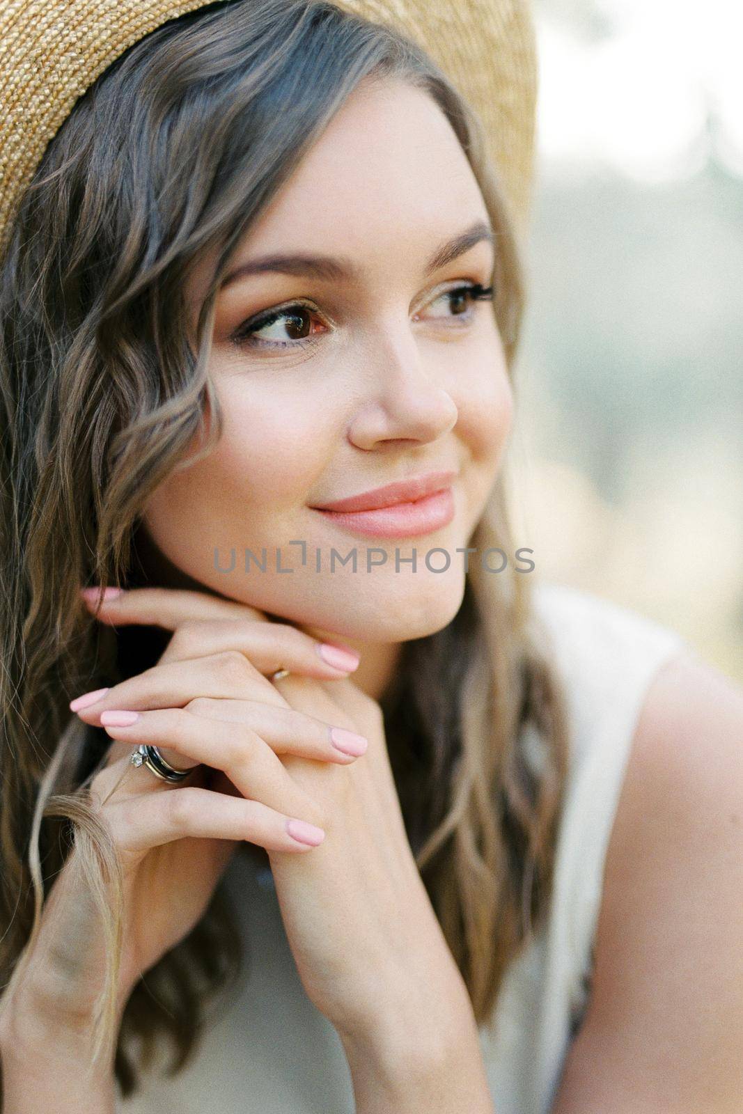 Smiling woman in a straw hat with her hands clasped under her chin. High quality photo