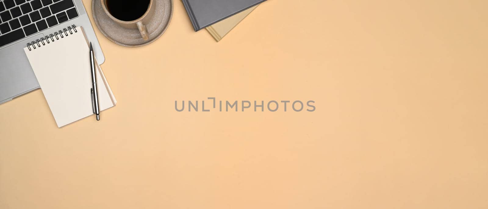 Top view notepad, laptop computer and cup of coffee on beige background.