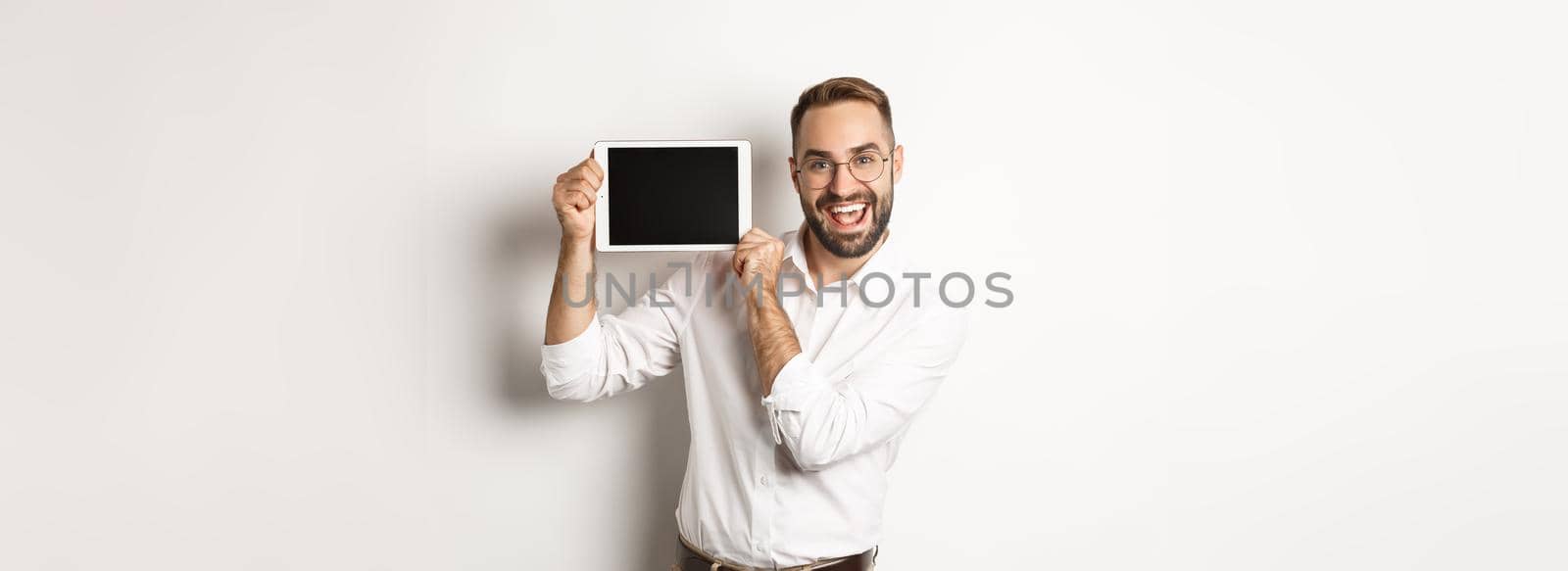 Shopping and technology. Handsome man showing digital tablet screen, wearing glasses with white collar shirt, studio background by Benzoix