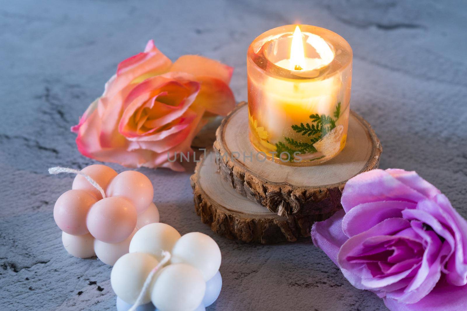 Lit resin art transparent candle on wood coaster with flowers showing the decoration of diwali, christmas, new year shot in pastel shades