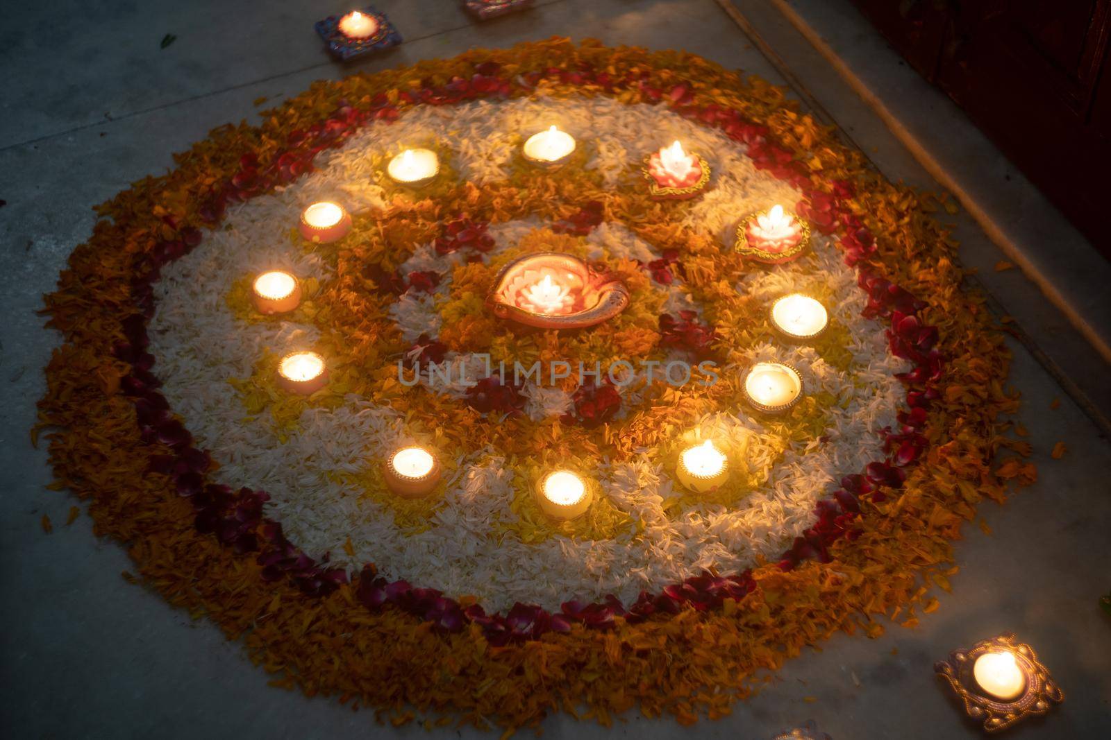 Rangoli, phooklam, hand made with flowers decorated with clay earthenware diya oil lamps showing the decoration on hindu festival of diwali
