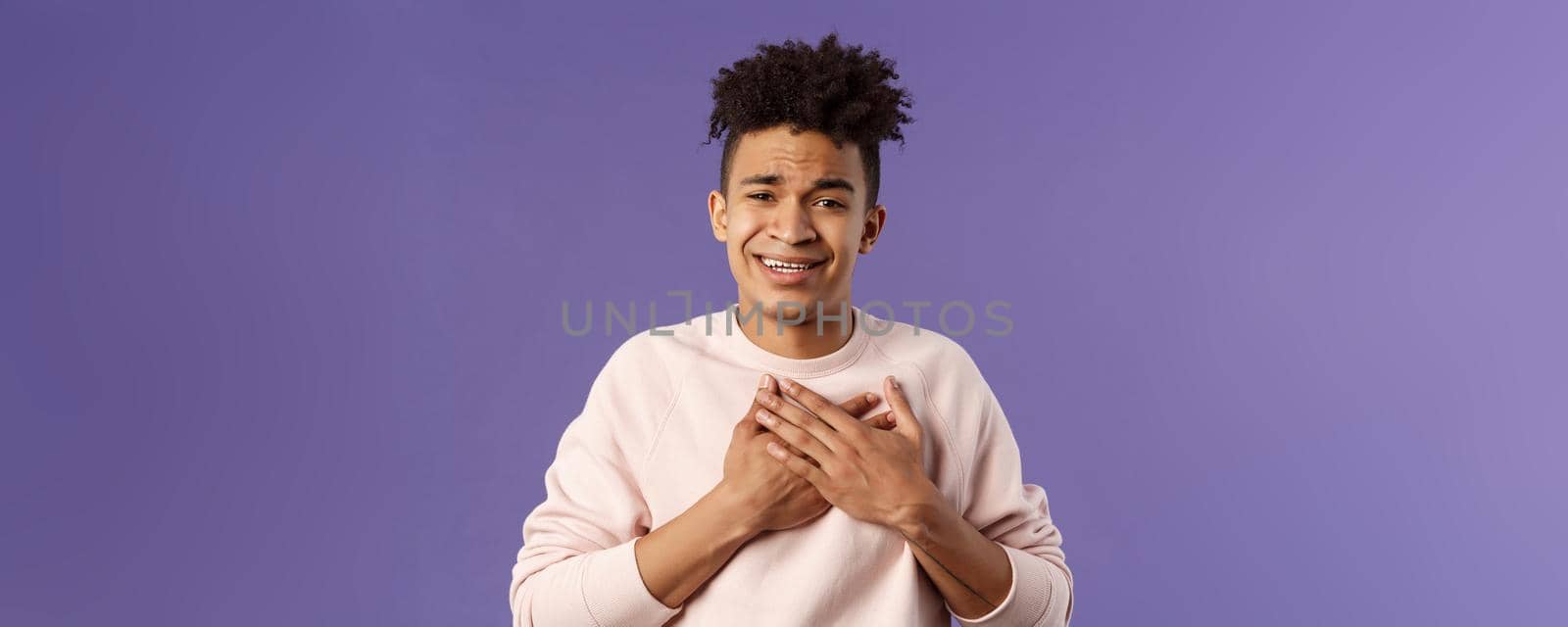 Close-up portrait of handsome silly hispanic guy with dreads, place hands on heart and sighing as contemplate something adorable speaking from all his soul, thanking for praises, purple background by Benzoix