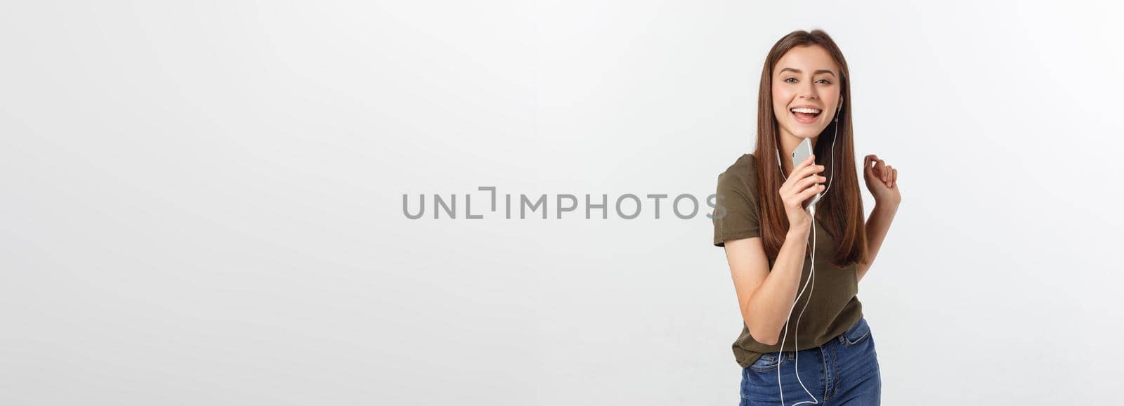 Portrait of a cheerful cute woman listening music in headphones and dancing isolated on a white background