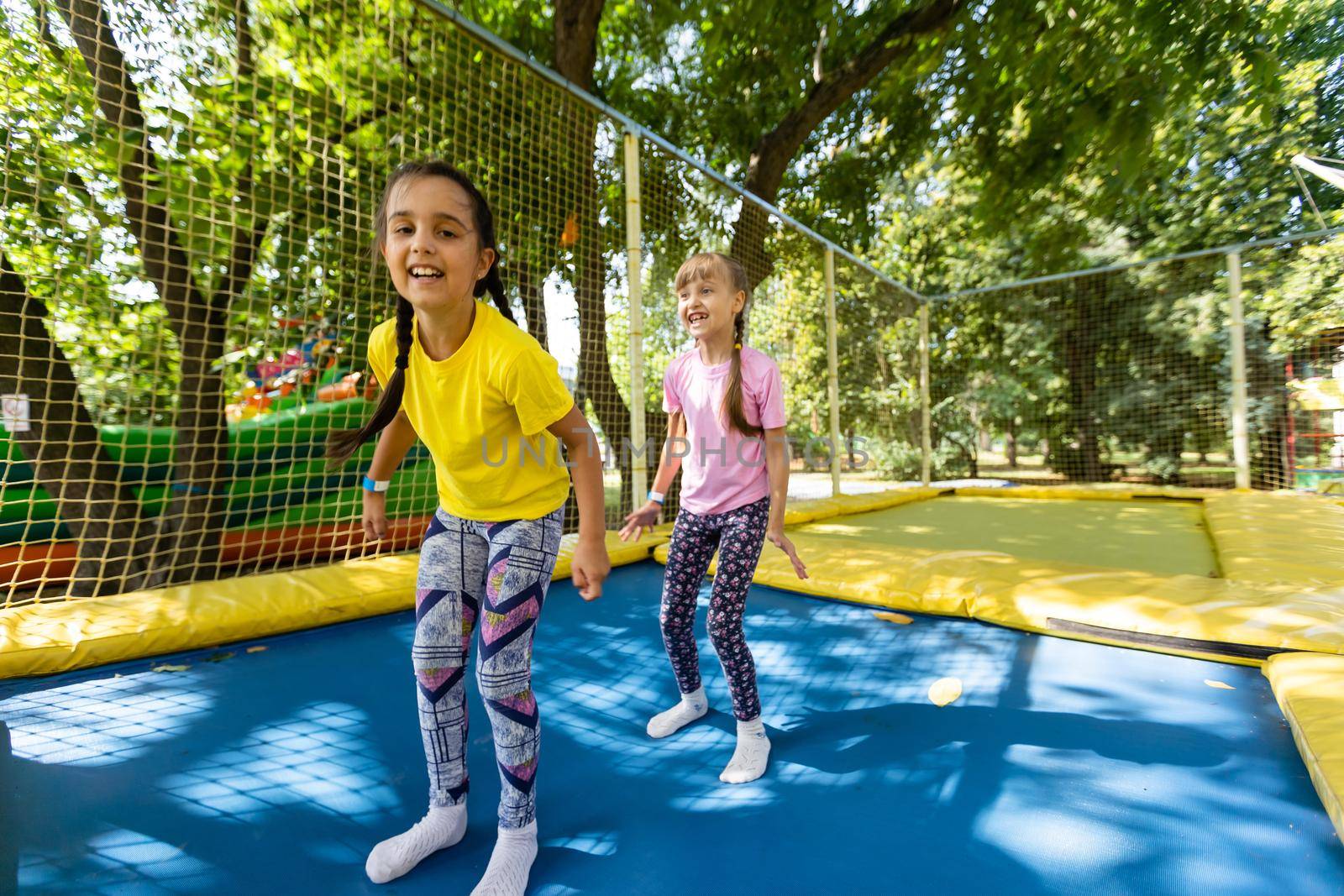 two girls jumping on a trampoline on a summer day