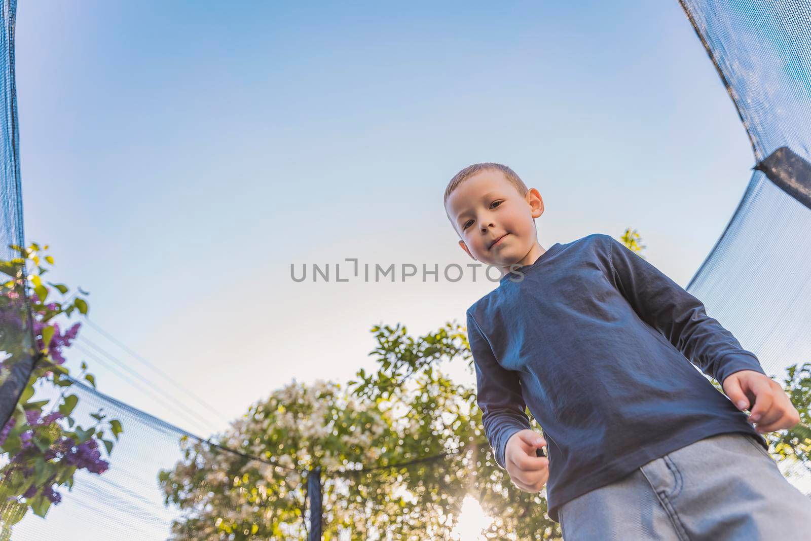 little boy jumps on a trampoline that stands in the yard