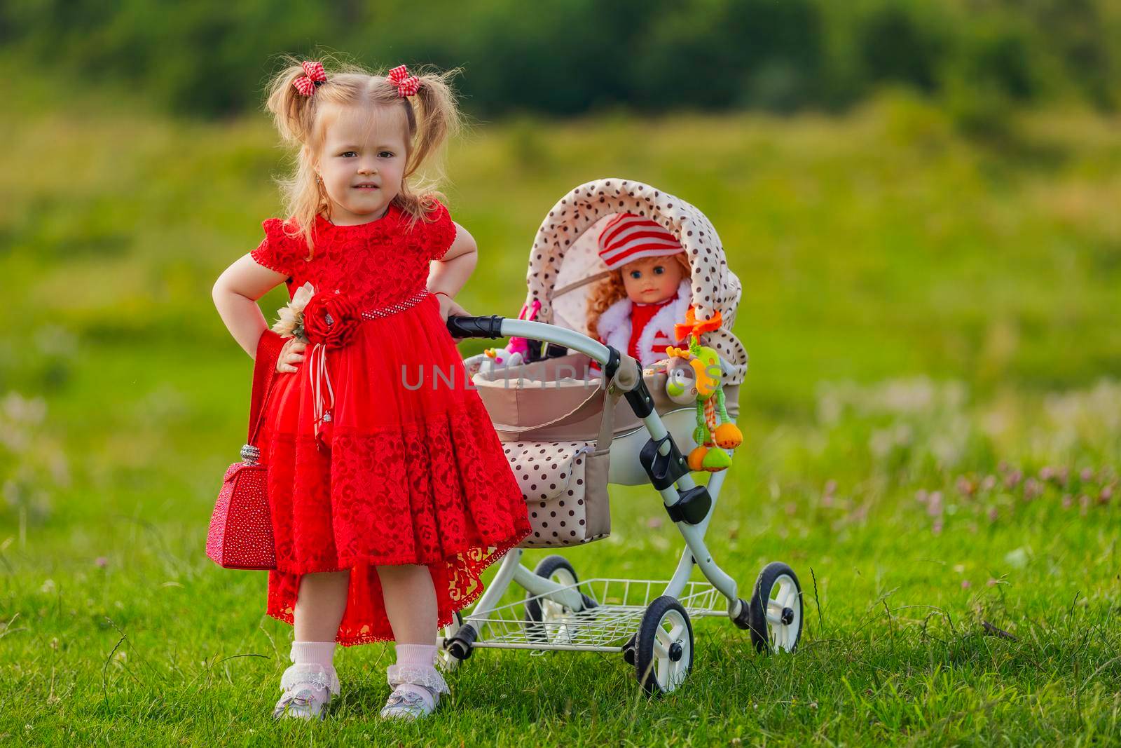 girl playing with a doll in a stroller in nature