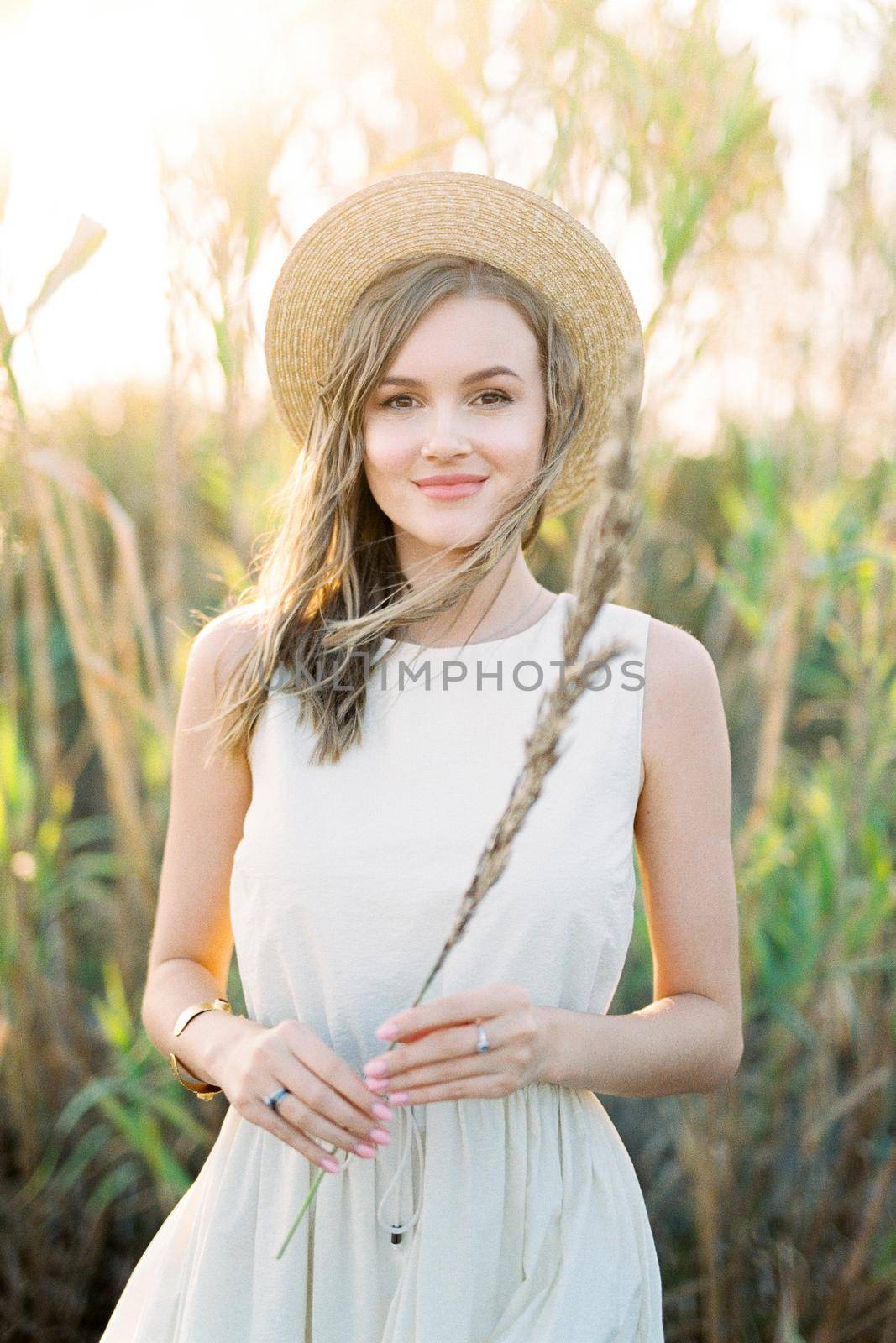 Girl in a straw hat stands with a dry cane in her hand. High quality photo