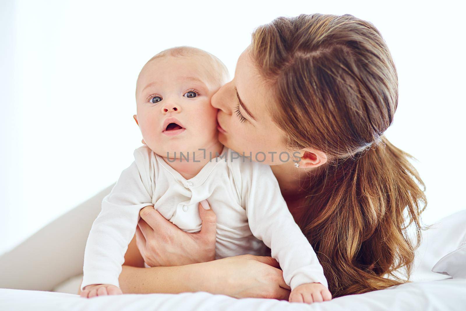 Kisses, cuddles and snuggles. a young mother bonding with her adorable baby boy at home