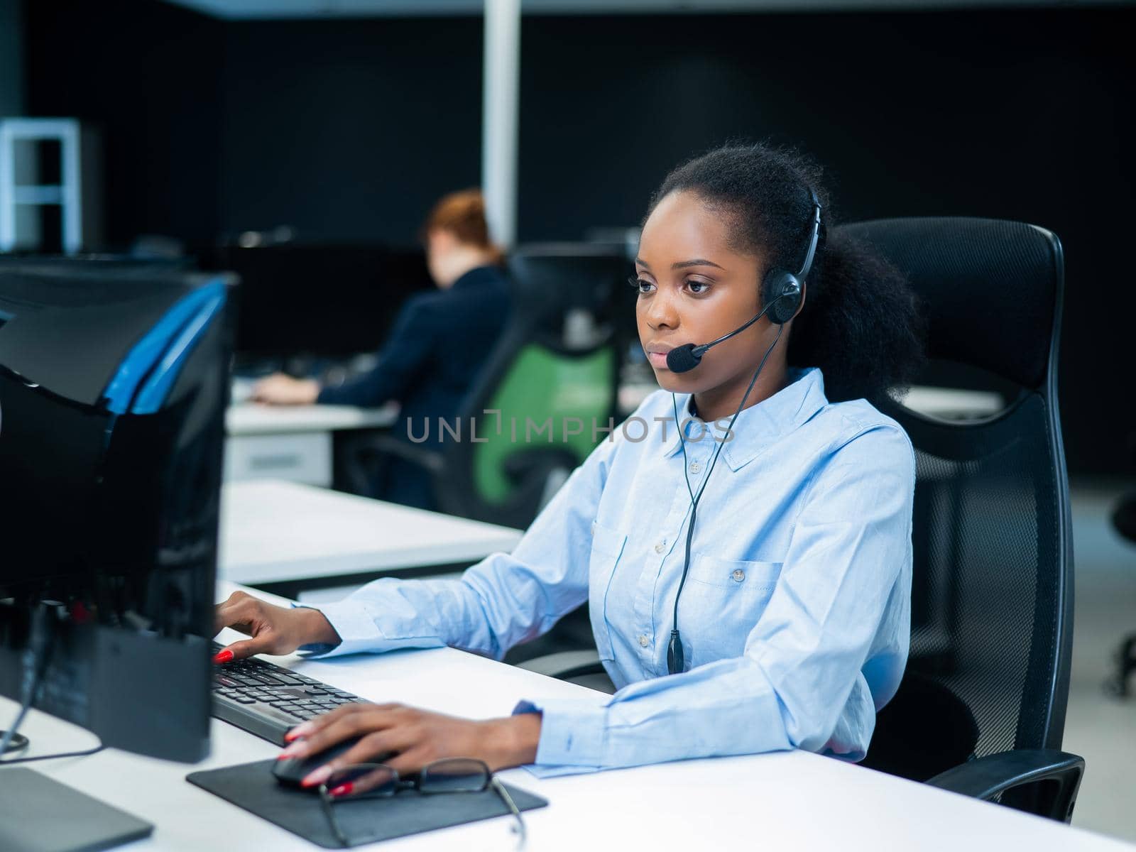 African young woman talking to a client on a headset. Female employee of the call center