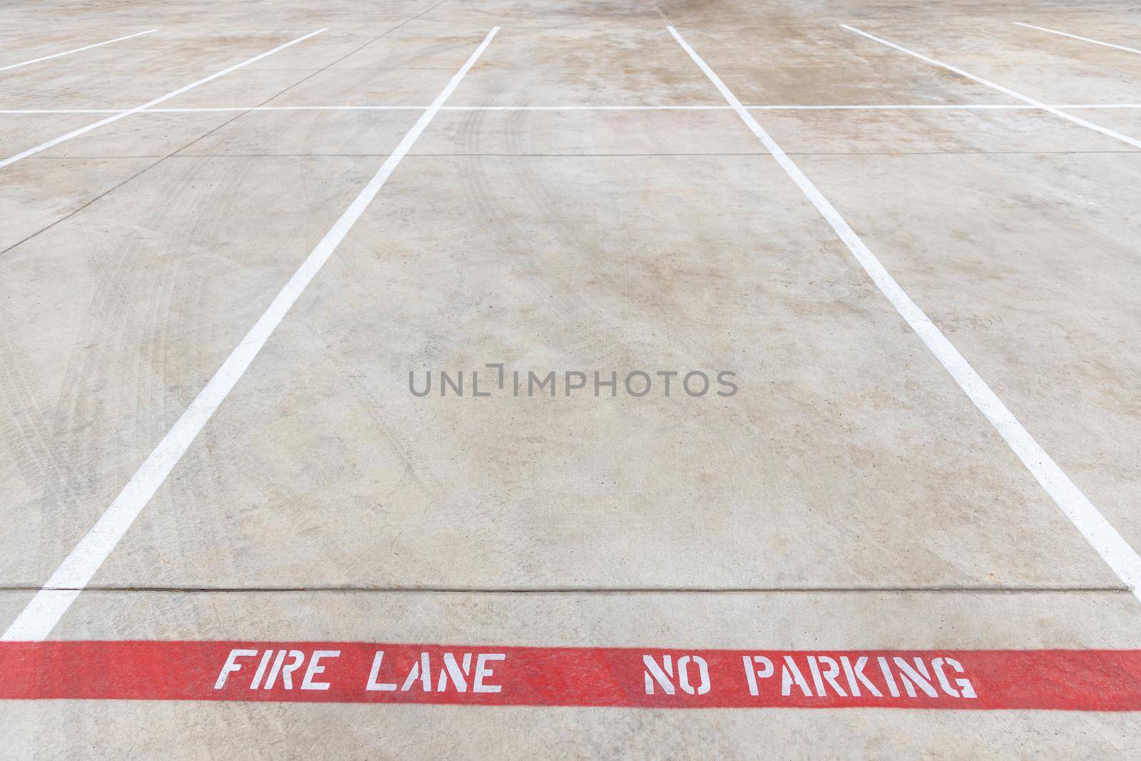 Fire lane no parking marking on the road of a parking lot, red line with white inscription on the asphalt, car parking is prohibited. by Khosro1