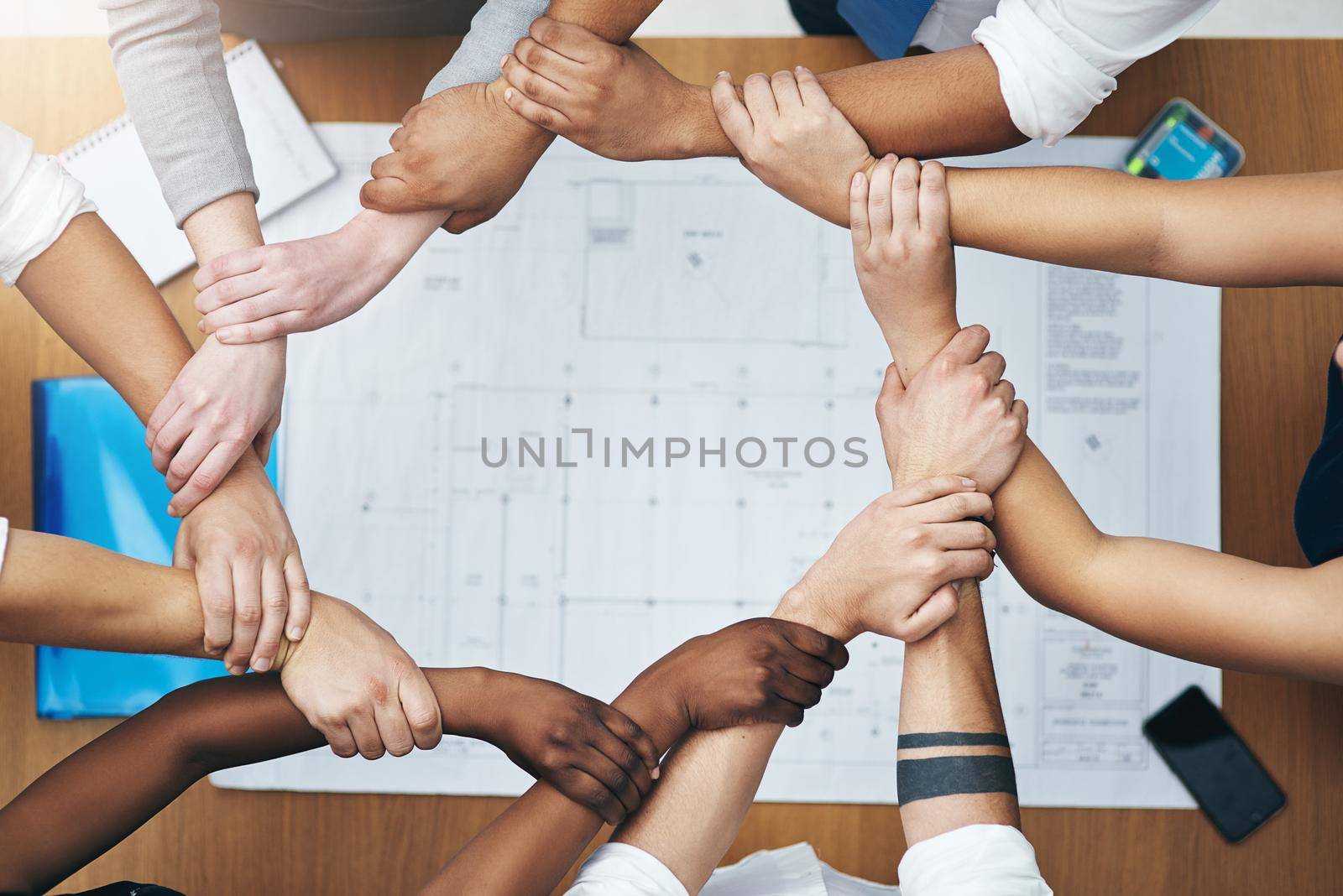 We are all connected as one. High angle shot of a group of unidentifiable people holding on to each other at the wrist