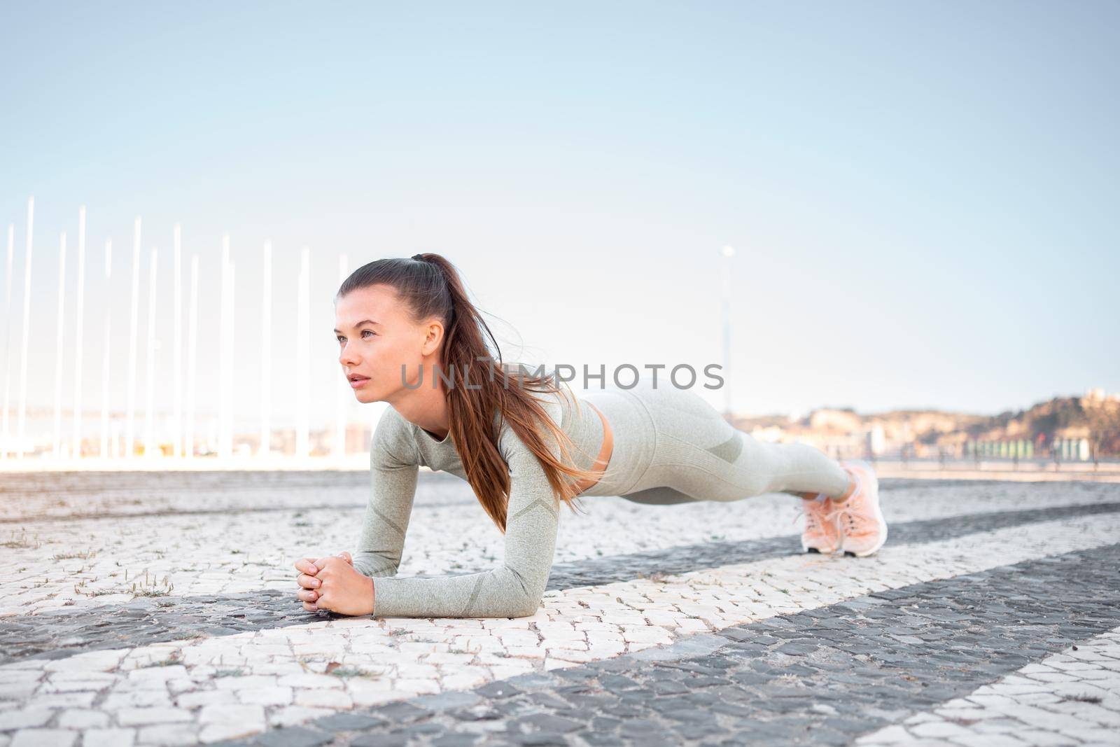 Full length, strong fit girl sportswear training plank outdoor by andreonegin