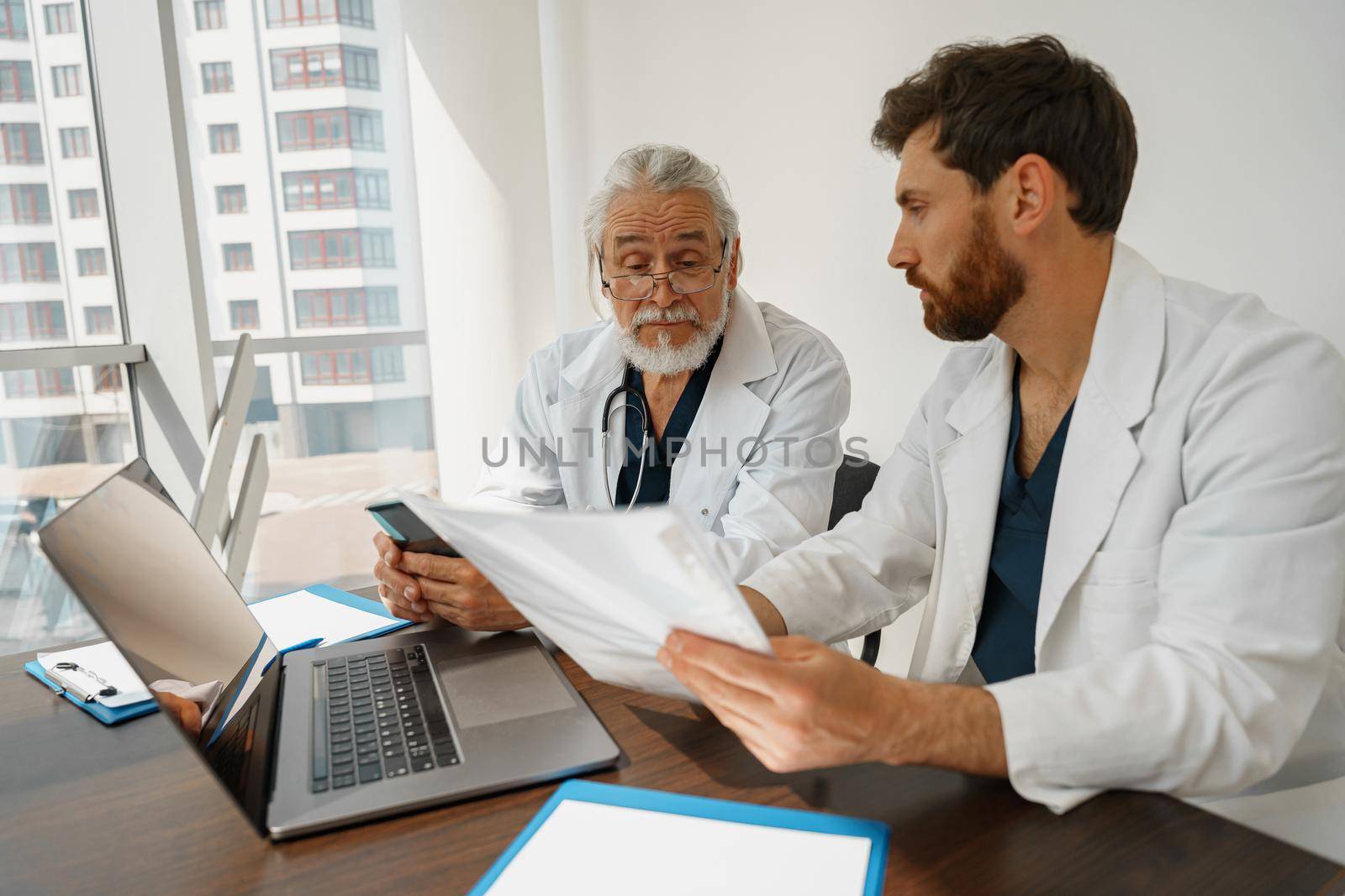 Two doctor colleagues discussing patient diagnosis sitting in office of medicine clinic