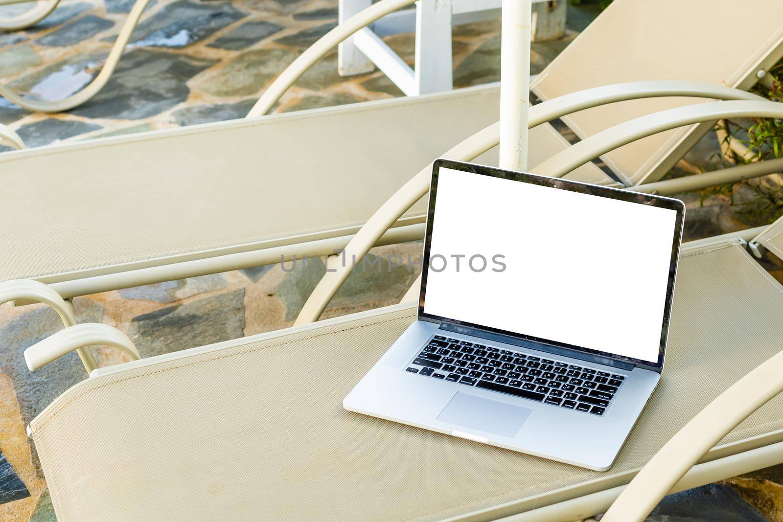 grey laptop computer open with keyboard on deckchair.