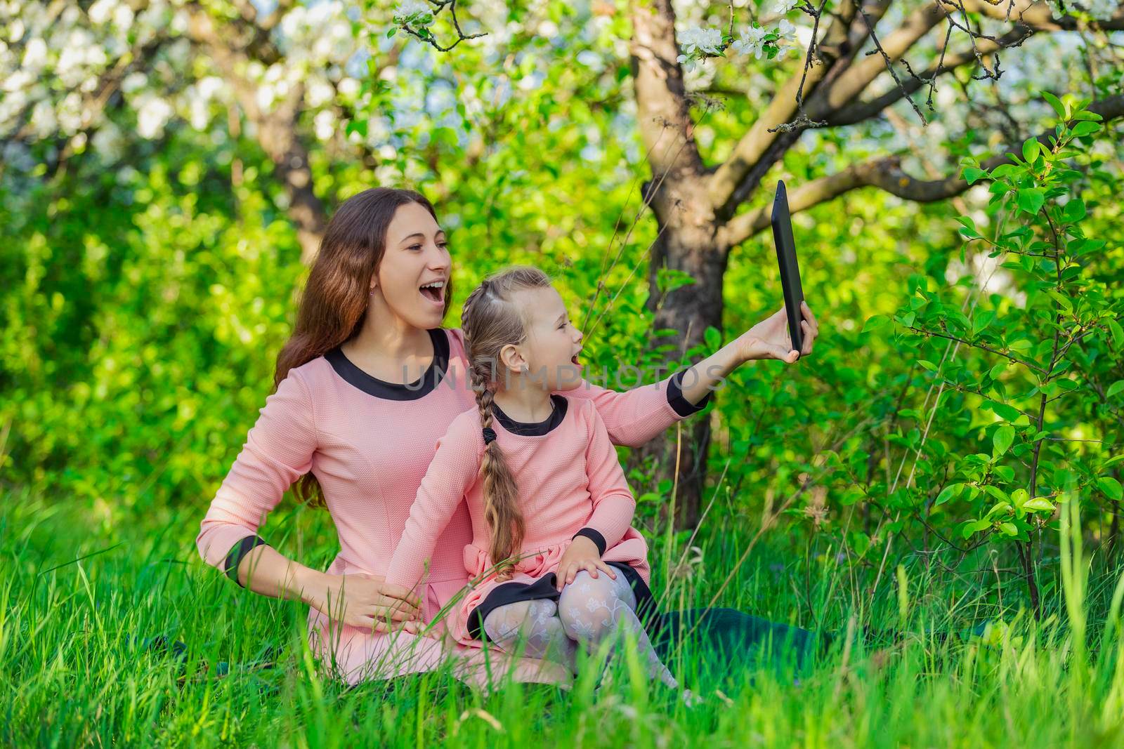 mother and daughter take pictures using a tablet in nature