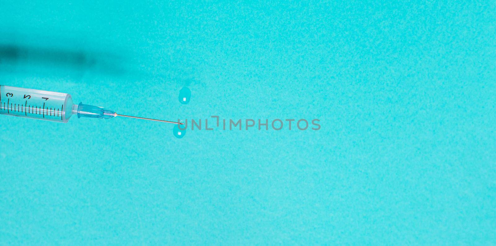 Syringe with vaccine on blue background from above by Ciorba
